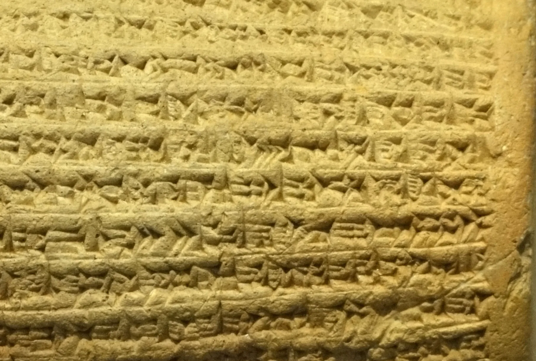 A close view shows dense rows of wedge-shaped impressions and horizontal grooves on a yellow-brown clay surface.