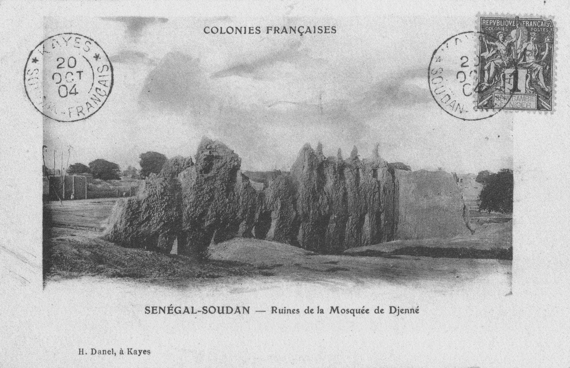 A black-and-white French colonial postcard, postmarked 1904, showing crumbling, eroded mud walls standing in an empty open space.