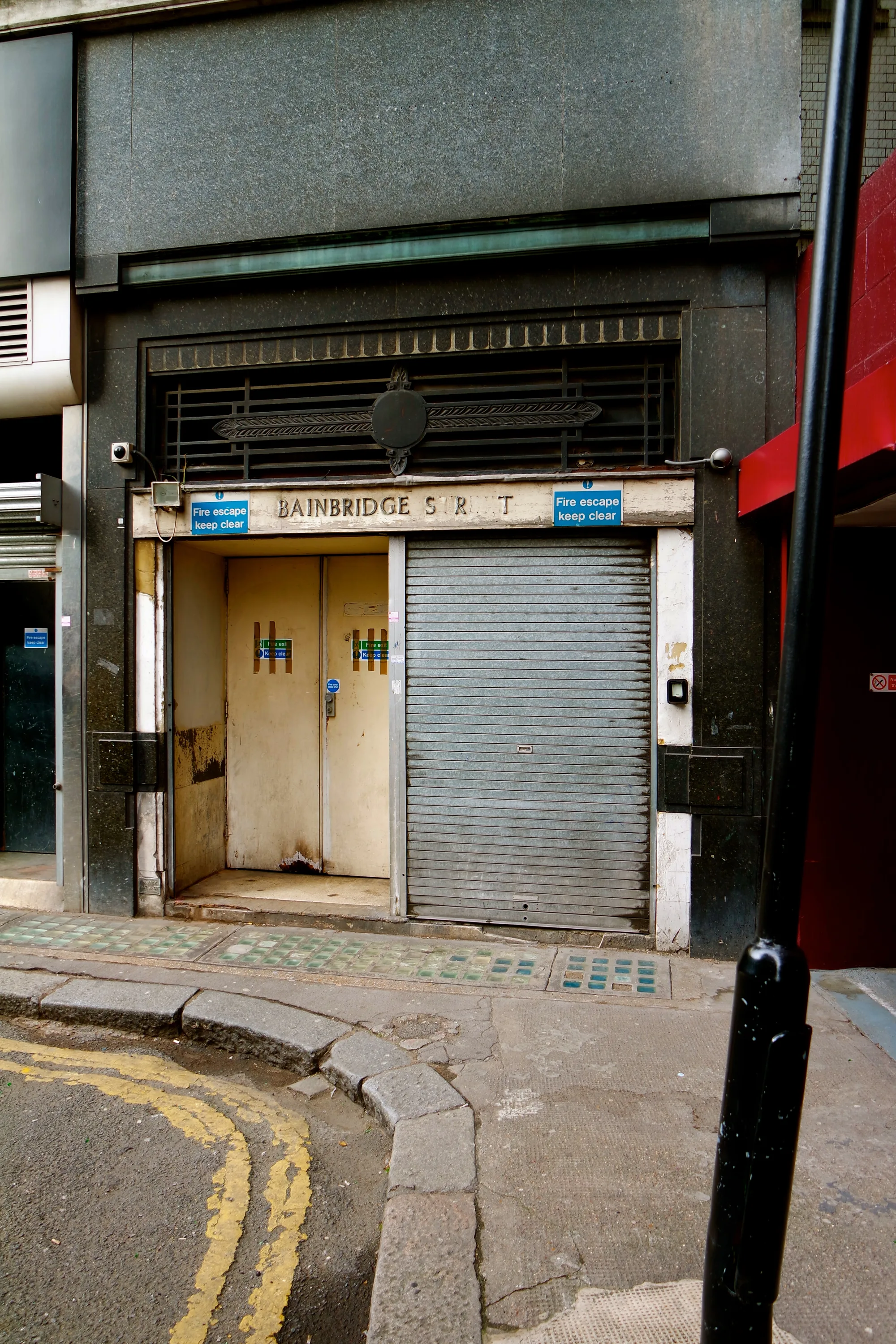 A plain fire exit door set into the high rear wall of the Dominion Theatre on Bainbridge Street.