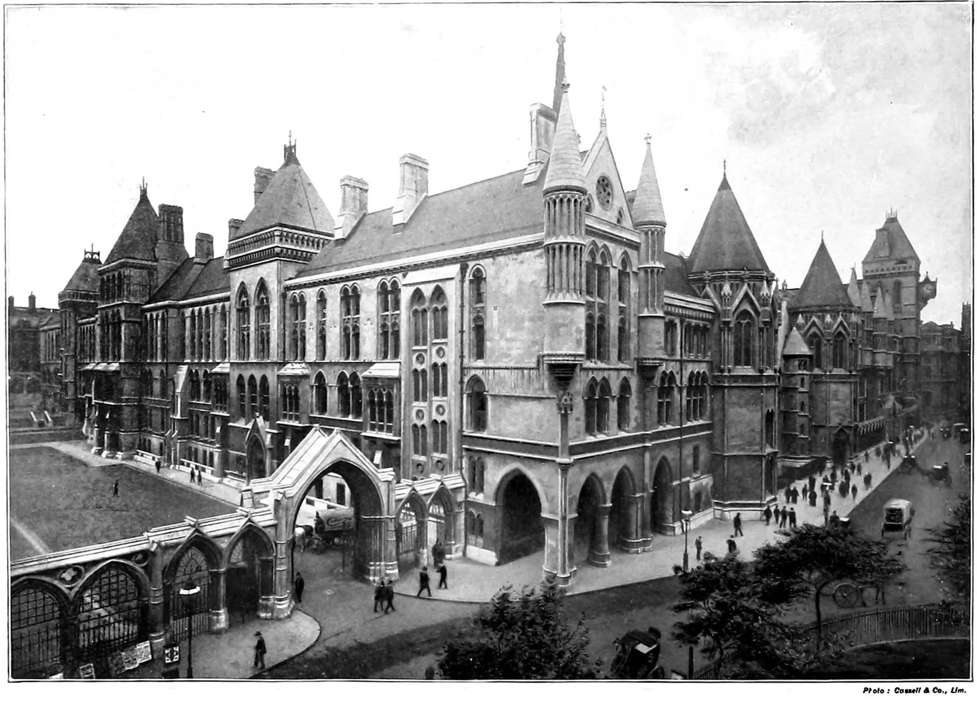 A black-and-white late Victorian view of the Royal Courts of Justice, a long Gothic building with towers, seen from the Strand with carriages in the street.